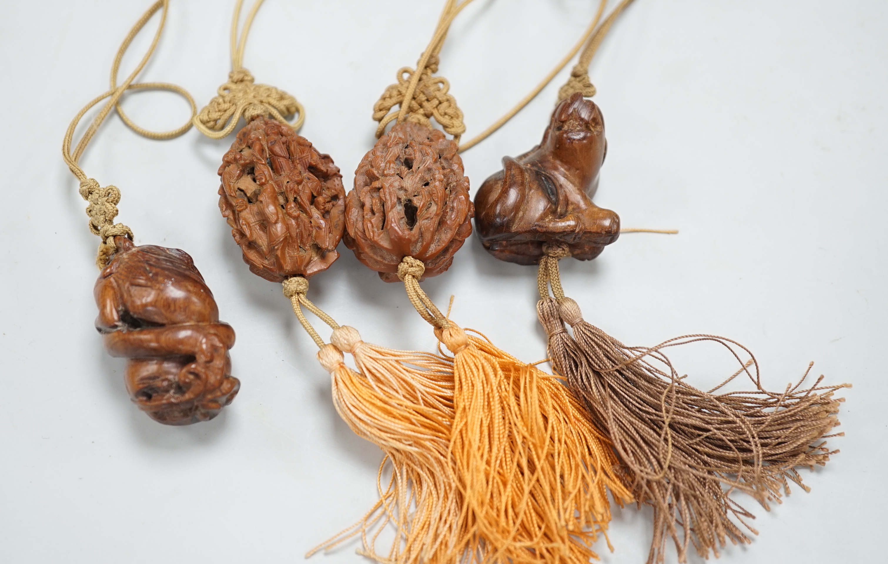 Two Chinese peach stone carvings and two carved wood toggles on a silk cord
